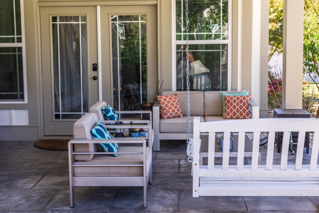 Covered outdoor patio in a new construction house home with guest seating.